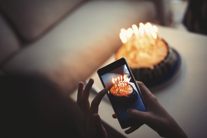 En mobiltelefon som tar bilde av en bursdagskake med bursdagslys